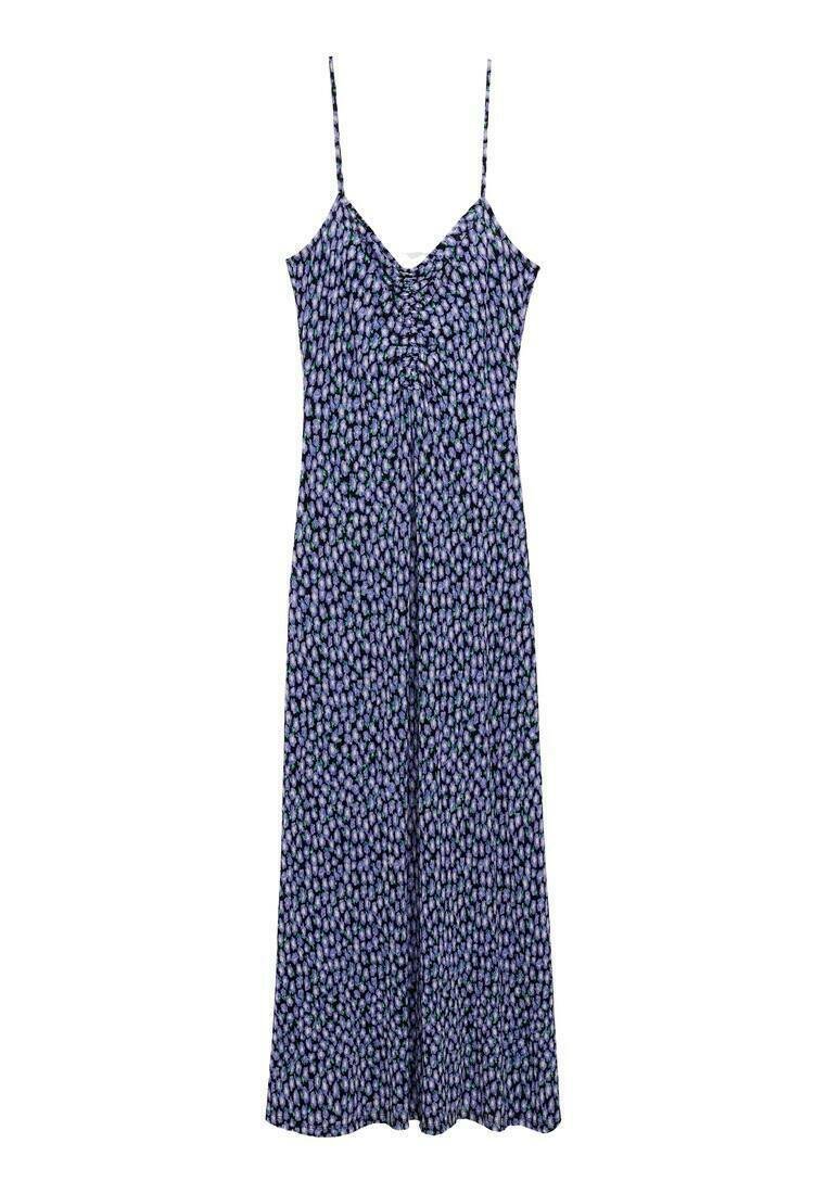 Robe maxi à motifs violets avec des fines bretelles, un corsage ajusté et une jupe fluide. Le tissu a une texture douce et légère.