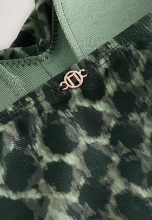 Vihreä kangas, jossa on teksturoitu, abstrakti kuvio tummissa ja vaaleissa sävyissä. Kauluksen läheisyydessä ruusukultainen metallikoriste.