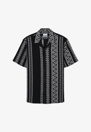 Kurzärmliges schwarz-weißes Hemd mit geometrischen Mustern und markanten Streifen. Mit Knopfleiste und Kragen.