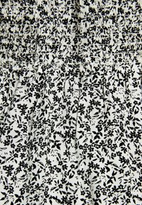 Black and white floral patterned fabric with gathered texture. Features small flowers and leaves, creating a dense, contrasting design.