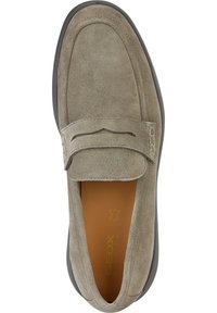 Mocassino in suede grigio con suola in gomma, dotato di una fascia imbottita e dettagli di cucitura sottili. L'interno è marrone chiaro con stampa del logo.