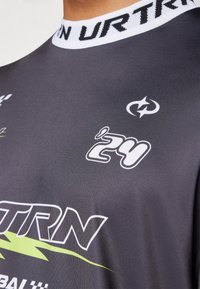 Harmaa urheilu paita, jossa on valkoinen ribbineck-kotelo, valkoisia ja vihreitä painettuja logoja sekä huomattava '24' yksityiskohta. Sujuva tekstiilifinish.