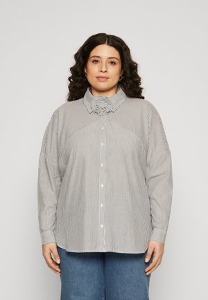 Blouse rayée avec un col montant, fermeture à boutons et coutures d'épaule abaissées. Le matériau a une texture lisse dans des couleurs monochromes.