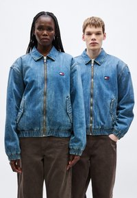 Džínové bomber bundy svetlomodrej farby, s elastickými manžetami a lemom, zapínanie na zips a bočné vrecká. Na hrudi je logo nášivka.
