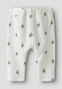 Vita ribbade leggings med ett mönster av gröna fåglar, med ett elastiskt midjeband och åtsittande ankelslut. Texturerad väv ger djup.