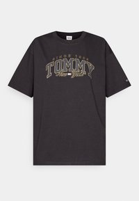 Černé bavlněné tričko s krátkými rukávy, které má zlatou vyšívanou značku "TOMMY New York" a text "since 1985" v zakřiveném designu.