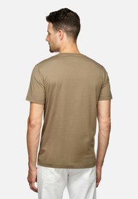 Camiseta de manga corta color caqui, diseño de cuello redondo, textura de tela suave, corte relajado, vista desde la parte posterior, con detalles mínimos.