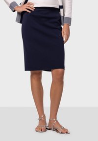 Navy-hyttinen kynähame, jossa on sileä pinta, polvipituinen, varustettu istuvalla muotoilulla ja etutaskuilla. Yhdistetty hopeisiin hihnasandaaleihin.