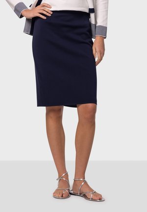 Jupe crayon bleu marine avec une texture lisse, longueur genoux, présentant un design ajusté et des poches avant. Associée à des sandales à talons argentées.