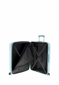 Maleta rígida en azul claro, con un interior negro que incluye correas cruzadas, un compartimento con cremallera y ruedas que giran suavemente.