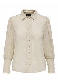 Beżowa bluzka z zapięciem na guziki z przodu, wykończona teksturowanym wzorem w kropki, z kołnierzykiem i bufkami przy rękawach zakończonymi gumkami.