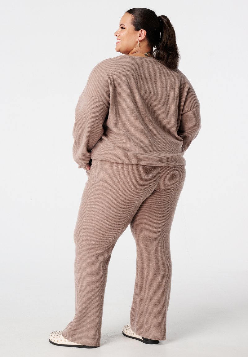 Twee-delige geribde trui set in taupe, met een ontspannen pasvorm, verlaagde schouders en flared broeken. Zachte textuur en subtiele details.