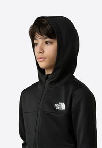 Čierna mikina na zips vyrobená z mäkkého materiálu, s predným bielym logom a priliehavým strihom s kapucňou a bočnými švami.