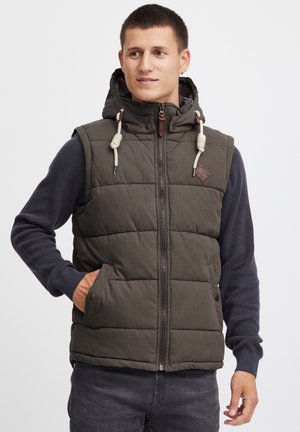 Padded olive green vest with a hood, front zipper, and drawstring accents. Features side pockets and a diamond-shaped logo patch.