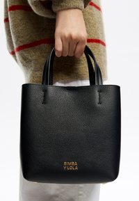 Czarna torebka typu tote wykonana ze skóry o teksturowanym wykończeniu, posiadająca krótkie uchwyty i złote logo. Prosty, strukturalny design, bez widocznych wzorów.