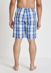 Blå och vit rutiga badshorts tillverkade av lättviktsmaterial med elastisk midja och ledig passform, med orange och gröna detaljer.