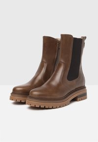 Bottines en cuir marron avec une texture lisse, des panneaux latéraux élastiques et une semelle en caoutchouc épaisse. Comprend une fermeture éclair sur le côté pour un enfilage facile.