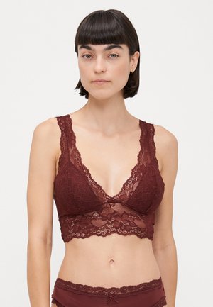 Kant bralette in diep bordeaux met een V-hals, geschulpte randen en verstelbare bandjes. Heeft een florale afbeelding en een cropped pasvorm.