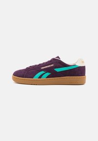 Violetti mokkasneakerit teal-vihreillä yksityiskohdilla, kumipohjalla ja kultaisella logo-yksityiskohdalla. Ominaisuuksiin kuuluu perinteinen matala muotoilu ja pyöreä kärki.