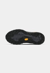 Black outsole with deep, multidirectional lugs for traction. Features a yellow Vibram logo near the center and textured patterns throughout.