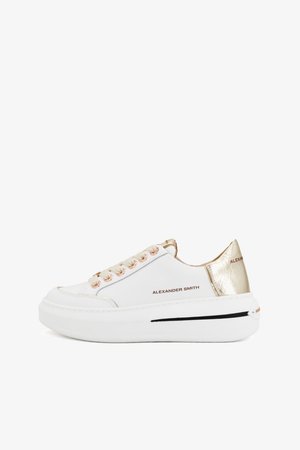 Witte sneakers met een glad leren bovenwerk, roségouden oogjes en een metallic gouden accent op de hak, met een chunky witte zool.