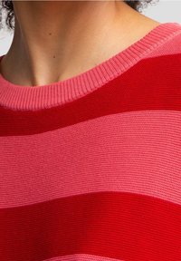 Pletený svetr s širokými horizontálními pruhy v červených a růžových tónech, s žebrovaným výstřihem a texturovanou tkaninou.