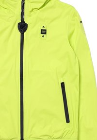 Giacca gialla neon realizzata in materiale leggero, con cerniera nera, dettagli tasca e cappuccio con cordino per regolazione.