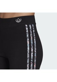 Svarta leggings med en floral mönstrad accent, tre vertikala ränder och en liten broderad logotyp på midjebandet.