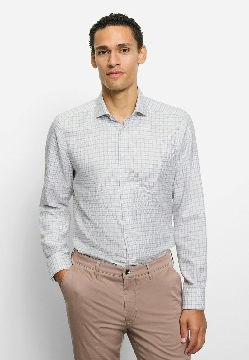 Hellgraues kariertes Hemd mit langen Ärmeln, Knopfleiste am Kragen und glattem Baumwollmischgewebe. Die Hose ist beige.