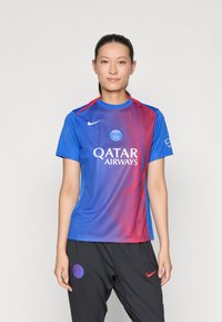 Mėlynas ir raudonas sportinis džersis trumpomis rankovėmis, turintis apvalų kaklą, logotipą ir rėmėjo tekstą. Medžiaga atrodo lygi, su gradientiniu dizainu.