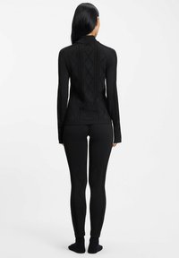 Czarna bluzka z długim rękawem i dopasowane legginsy z teksturowanymi wzorami w kształcie diamentów. Wykonane z elastycznego materiału, z kołnierzykiem.