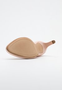 Zapato de tacón alto rosa con punta afilada y parte superior de sintético suave. La suela es de color beige con forma cónica y diseño de agarre mínimo.