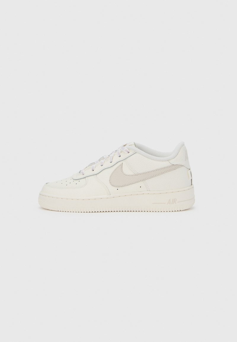 Λευκό αθλητικό παπούτσι Nike Air Force 1 με άνω μέρος από δέρμα, στρογγυλή μύτη, λεπτομέρειες με τρύπες και ουδέτερες αποχρώσεις. Λαστιχένια σόλα και μαξιλαρωμένος γιακάς.
