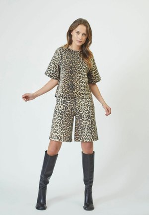 Leopard print outfit featuring a short-sleeve top and knee-length shorts, made from a smooth fabric. Paired with tall black boots.