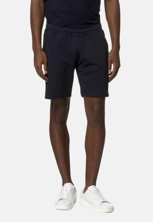 Pantaloni corti neri in tessuto morbido, con vita elastica e vestibilità comoda, abbinati a sneaker bianche.