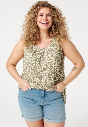 Haut sans manches vert et crème avec motif, détails plissés et ourlet, associé à un short en denim bleu avec rebords. Tenue d'été décontractée.