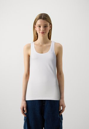 Canotta bianca realizzata in un tessuto morbido, con scollatura a barchetta e spalline larghe, abbinata a pantaloni in denim blu dal taglio ampio.