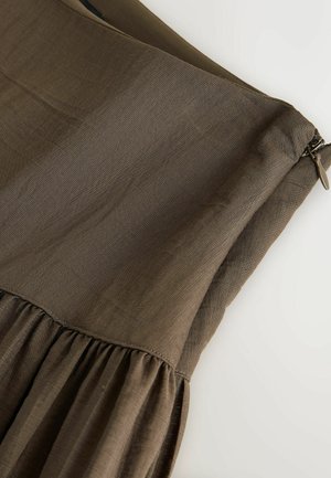 Brun kjole med en glat, tekstureret overdel og et rynket skørt. Inkluderer en sidelukning med lynlås.