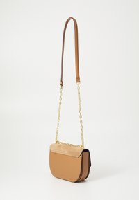 Borsa a tracolla in pelle tan con pattina in suede, tracolla dorata e forma arrotondata. Presenta una texture liscia e un branding minimale sul davanti.
