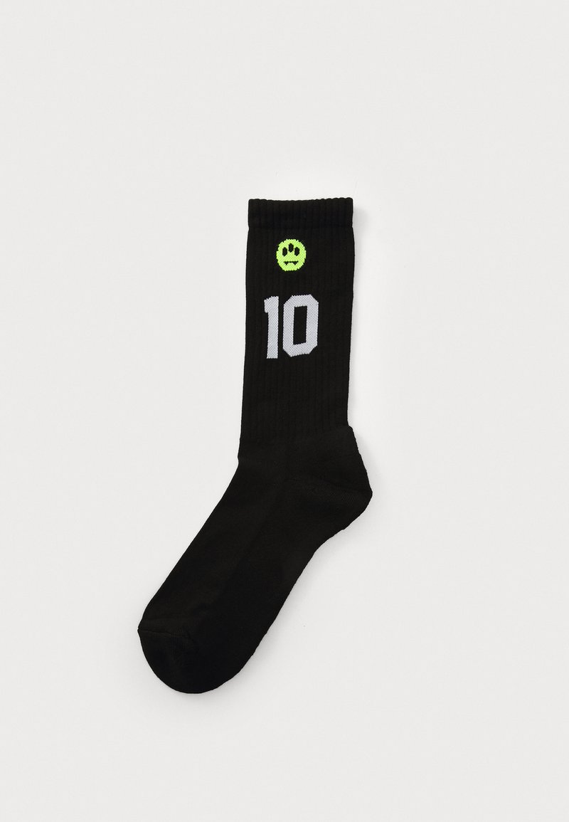 Chaussettes noires côtelées avec un visage souriant vert et le chiffre "10" en blanc sur le côté extérieur. Matériau doux avec une longueur standard jusqu'à la cheville.