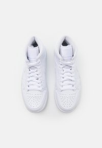 Valkoiset korkeavartiset tennarit, jotka on valmistettu sileästä synteettisestä materiaalista. Niissä on rei'itykset kärkiosassa, litteät nauhat ja pehmustettu nilkkatuki.