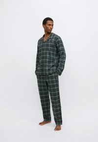 Set di pigiama a quadri in verde scuro e nero, con camicia con colletto e tasca frontale e pantaloni abbinati a taglio largo. Tessuto dalla texture morbida.