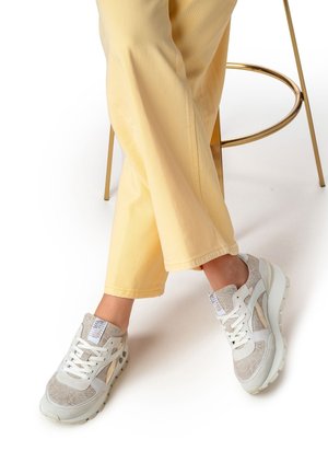 Sneakers con una combinazione di materiali grigio chiaro e crema, tessuto testurizzato, design con lacci e suola bianca spessa.