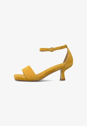 Sandalia amarilla de ante con punta abierta, correa en el tobillo, tacón bajo de bloque y punta cuadrada, vista lateral sobre fondo blanco.