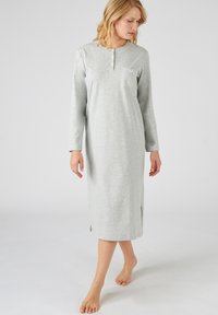 Camicia da notte grigia a maniche lunghe con scollatura henley, bottoni, fessure laterali e dettagli decorativi sulla tasca del petto in un tessuto morbido.