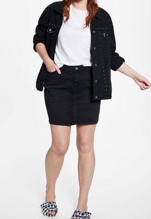 Černá denimová bunda se dekorativními cvočky, bílý tričko, černá denimová sukně a černobílé kostkované pantofle.