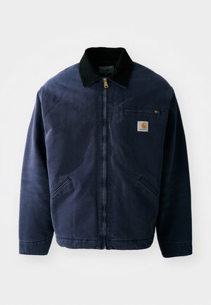 Giacca da lavoro blu navy con colletto in velluto a coste nero, chiusura frontale con zip, tasca sul petto e due tasche laterali. Tessuto liscio con una vestibilità strutturata.