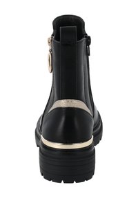 Botines negros que presentan una parte superior de cuero suave, acentos metálicos, una franja texturizada en el talón y una suela gruesa negra.
