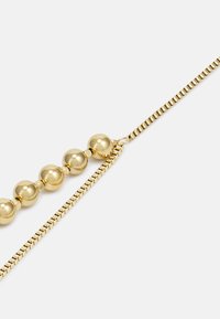 Gouden ketting met een ontwerp van gladde, sferische kralen en platte schakels. Bevat afwisselende patronen van kralen en schakels voor visuele interessante.