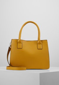 Borsa a mano in pelle gialla con forma strutturata. Presenta manici corti, tracolla removibile e dettagli di cucitura a contrasto.